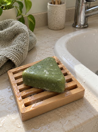 Savon Charmelle sur un porte-savon en bambou près du lavabo
