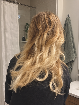 Longs cheveux blonds ondulés d'une testeuse, vus de dos