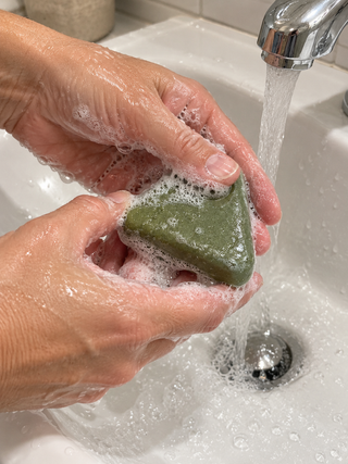 Mains qui font mousser le savon Charmelle au-dessus du lavabo