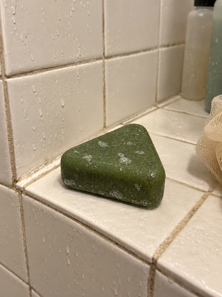 Savon Charmelle mouillé posé sur le rebord carrelé de la douche